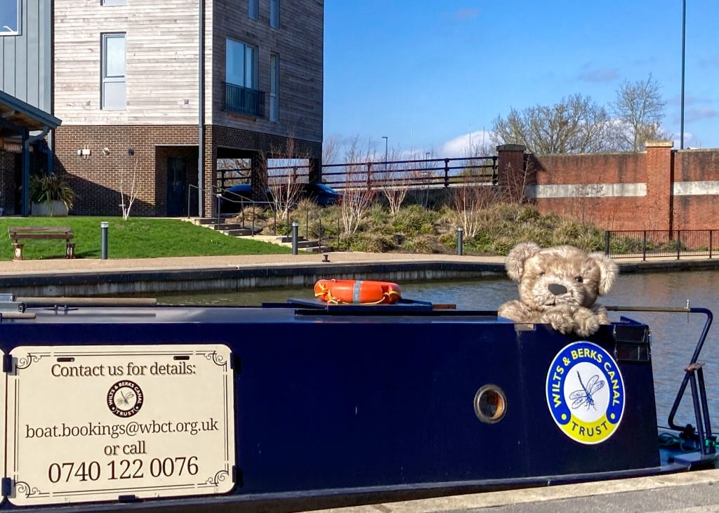Bentley the Bear, a realistic teddy bear costume posing on the Dragonfly, a narrowboat.